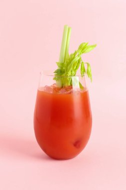 Pembe arka planda kerevizli bir bardak Bloody Mary.