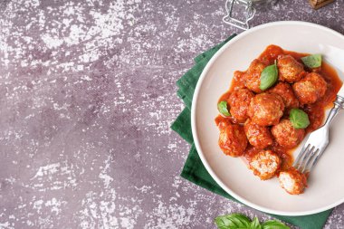 Domates soslu lezzetli köfte tabağı ve gri arka planda fesleğen.