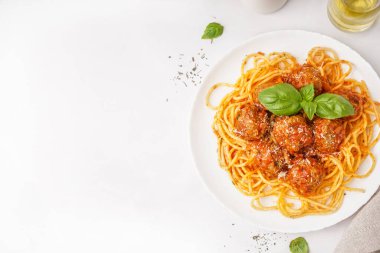 Bir tabak haşlanmış makarna, domates sosu ve beyaz masada köfte.