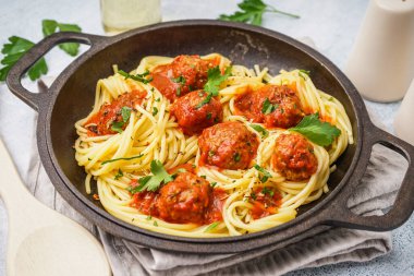 Domates soslu haşlanmış makarna tavası ve beyaz masada köfte.