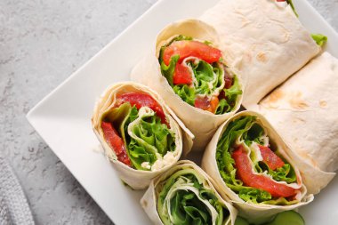 Gri arka planda sebzeli lezzetli lavaş ruloları.