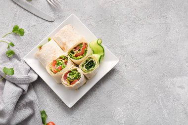 Gri arka planda sebzeli lezzetli lavaş ruloları.