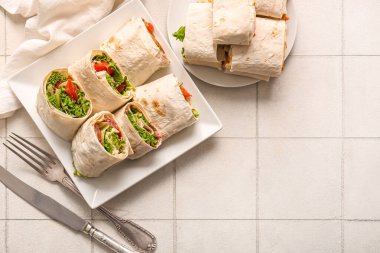 Beyaz fayanslı domatesli ve yeşillikli leziz lavaş ruloları.