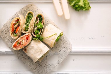 Beyaz ahşap arka planda sebzeli lavaş ruloları.