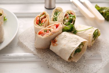 Beyaz ahşap arka planda sebzeli lavaş ruloları.