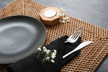 Temiz tabağı olan güzel bir masa, çingene çiçekleri, siyah masa örtüsü ve mumu.