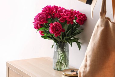 Dolapta kırmızı şakayık vazosu var.