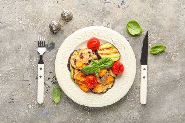 Izgara sebzeli tabak ve gri arka planda fesleğen.