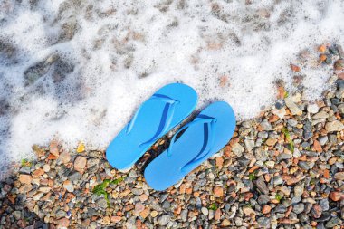 Deniz kıyısında mavi parmak arası terlikler