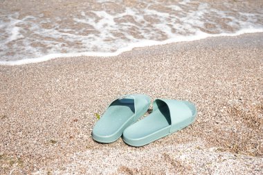 Deniz kıyısında turkuaz parmak arası terlikler