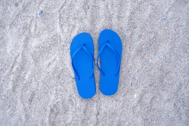 Kumsal arka planında mavi parmak arası terlikler