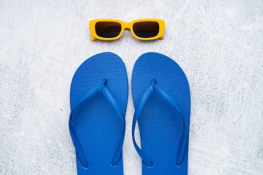 Grunge arka planında güneş gözlüklü mavi parmak arası terlikler