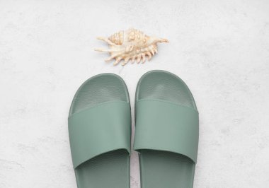 Beyaz grunge arka planında kabuklu turkuaz parmak arası terlikler