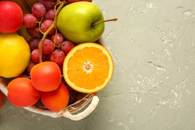 Gri arka planda farklı taze meyvelerle dolu sepet.