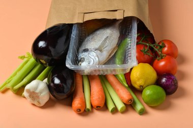 Turuncu zemin üzerinde farklı ürünler olan kağıt torba.