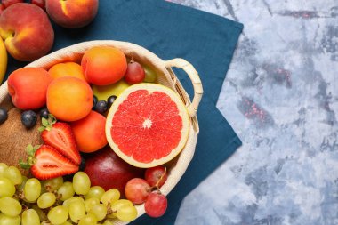 Mavi arka planda farklı taze meyvelerle dolu bir sepet.