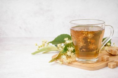 Beyaz arka planda cam bardak ıhlamur çayı olan tahta.