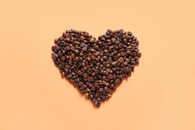 Turuncu arka planda kahve çekirdeklerinden yapılmış kalp.