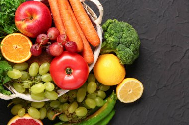 Siyah arka planda farklı taze meyve ve sebzelerle dolu bir sepet.