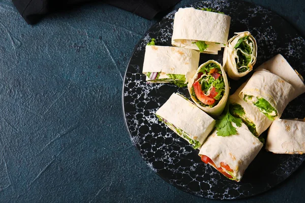 stock image Board of tasty lavash rolls with vegetables and greens on black background