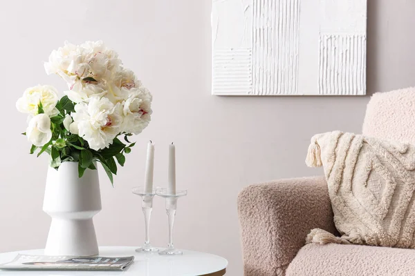 灰色の壁の近くにコーヒーテーブルとアームチェア付きの白い牡丹の花瓶 — ストック写真