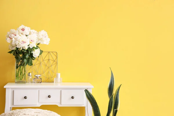 黄色の壁の近くのドレッシングテーブルと観葉植物と白い牡丹の花瓶 — ストック写真