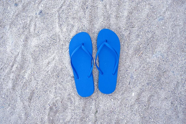 砂のビーチの背景に青いフリップフロップ — ストック写真