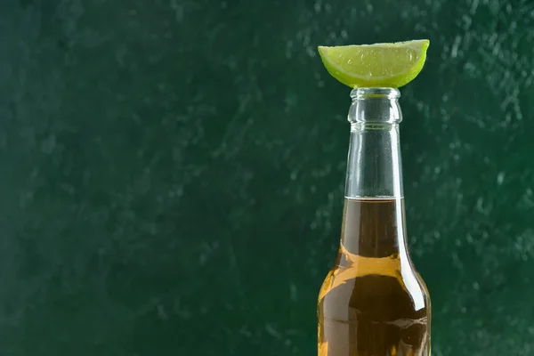 緑の背景にライムと冷たいビールのボトル — ストック写真