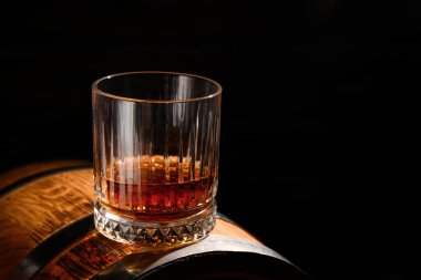 Siyah zemin üzerinde bir bardak rom olan fıçı.