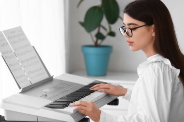 Genç bayan müzisyen evde sentezleyici çalıyor.