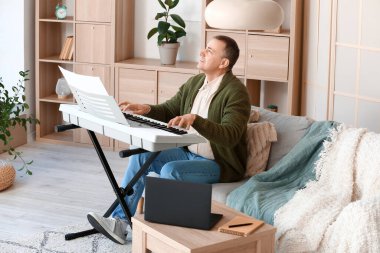 Evde sentezleyici çalan olgun bir adam