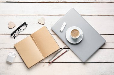 Not defteri, dizüstü bilgisayar, bir fincan kahve ve bardakla beyaz ahşap masada kompozisyon