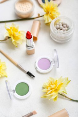 Beyaz arka planda farklı kozmetik ürünleri olan güzel nergisler.