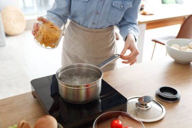 Genç bayan mutfakta makarna pişiriyor, yakın plan.