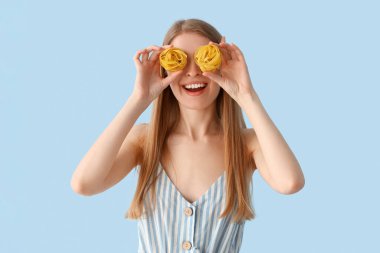 Mavi arka planda çiğ makarna olan genç bir kadın.