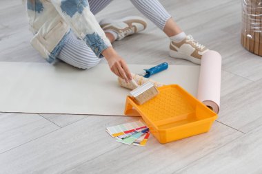 Evde duvar kağıdı yapıştıran genç bir kadın, yakın plan.