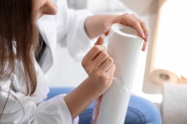 Odasında duvar kağıdı yuvarlanan genç bir kadın.