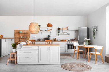 Şık buzdolabı, tezgah, raflar ve masalı aydınlık mutfağın içi.