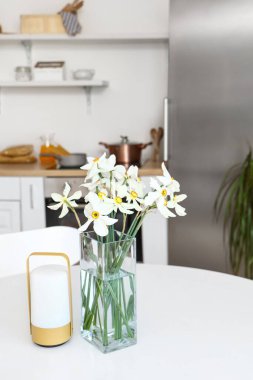 Narkissus çiçekli vazo ve mum ışık mutfağının iç tarafında, yakın plan.