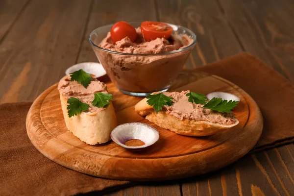 stock image Board with bowl of delicious pate and sandwiches on wooden background, closeup