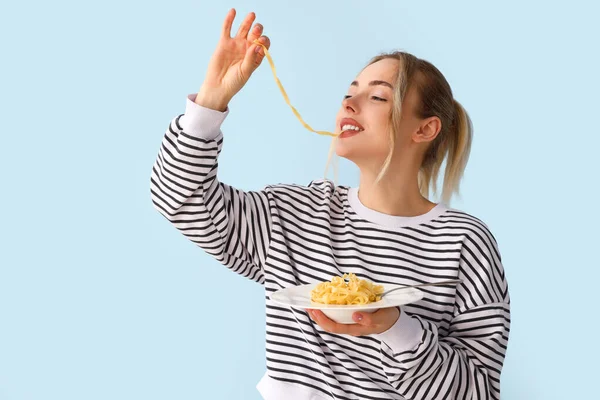 青い背景でおいしいパスタを食べる若い女性 — ストック写真