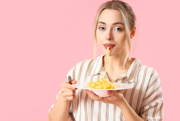年轻女人在粉色背景下吃着美味的意大利面 特写镜头 — 图库照片