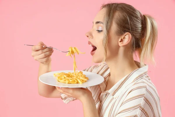 年轻女人在粉色背景下吃着美味的意大利面 特写镜头 — 图库照片