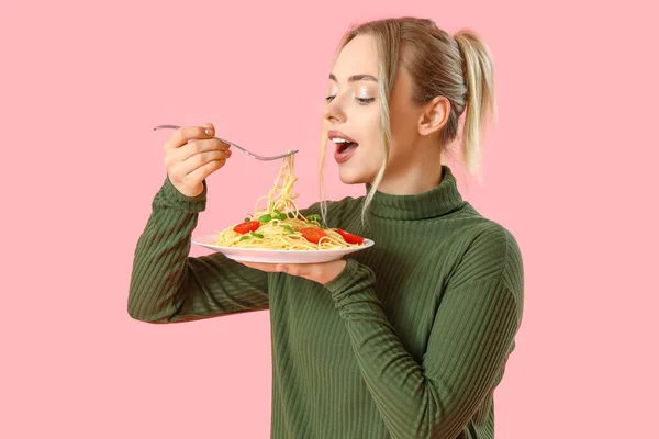 粉红背景的年轻女人吃着美味的意大利面 — 图库照片