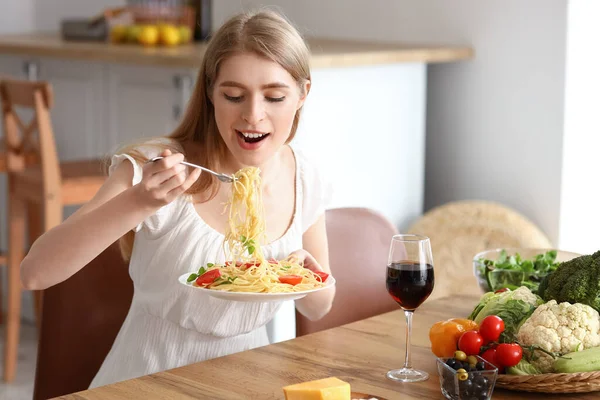 若い女性食べるおいしいパスタでキッチン — ストック写真