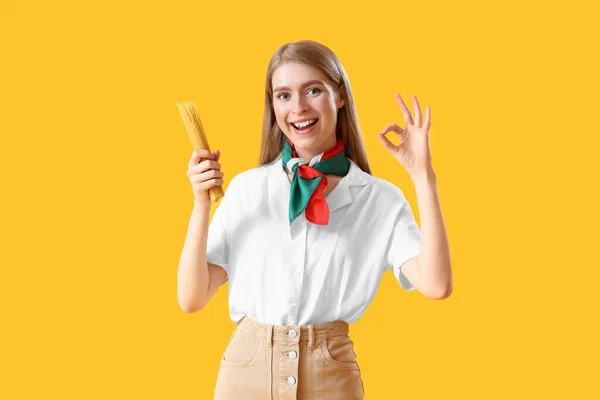 Młoda Kobieta Surowym Spaghetti Pokazuje Żółtym Tle — Zdjęcie stockowe