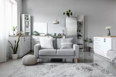 Şık buzdolabı, tezgah, kanepe ve raf üniteleriyle aydınlık mutfağın içinde.