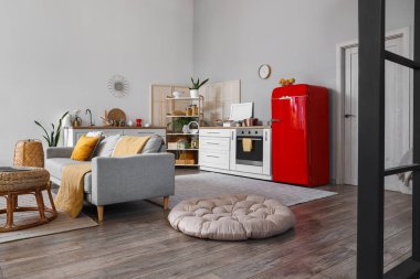 Mutfağın içinde kırmızı buzdolabı, tezgah ve kanepe var.