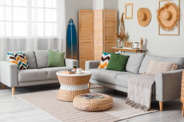 Sörf tahtası, masa ve kanepelerle aydınlık oturma odasının içinde.