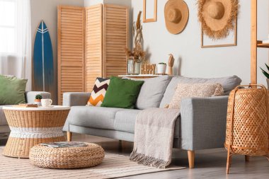 Sörf tahtası, masa ve kanepelerle aydınlık oturma odasının içinde.